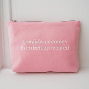 The Pouch from Numi, a pink cotton canvas bag with a zipper, with a quote that says "Confidence comes from being prepared".