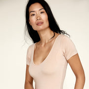 Woman wearing The Bodysuit, a sweatproof undershirt from Numi in light beige