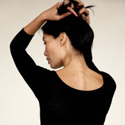 Woman holding her hair up, wearing The Three Quarter undershirt from Numi in black