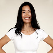 Woman smiling while wearing The Lace undershirt from Numi in white, showing the crew neck