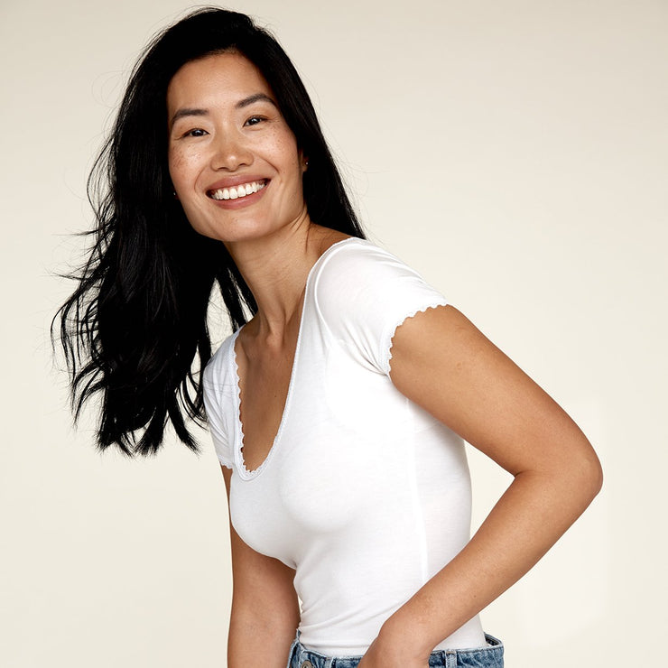 Woman smiling while wearing The Lace undershirt from Numi in white